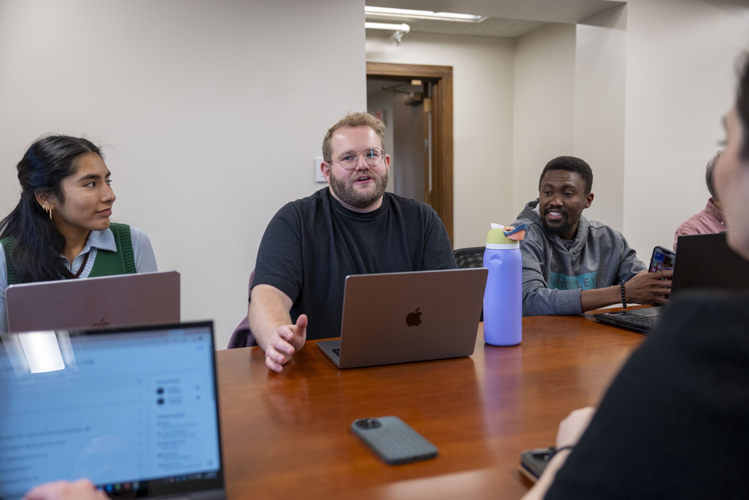 students in a classroom with laptops discussing lecture topics
