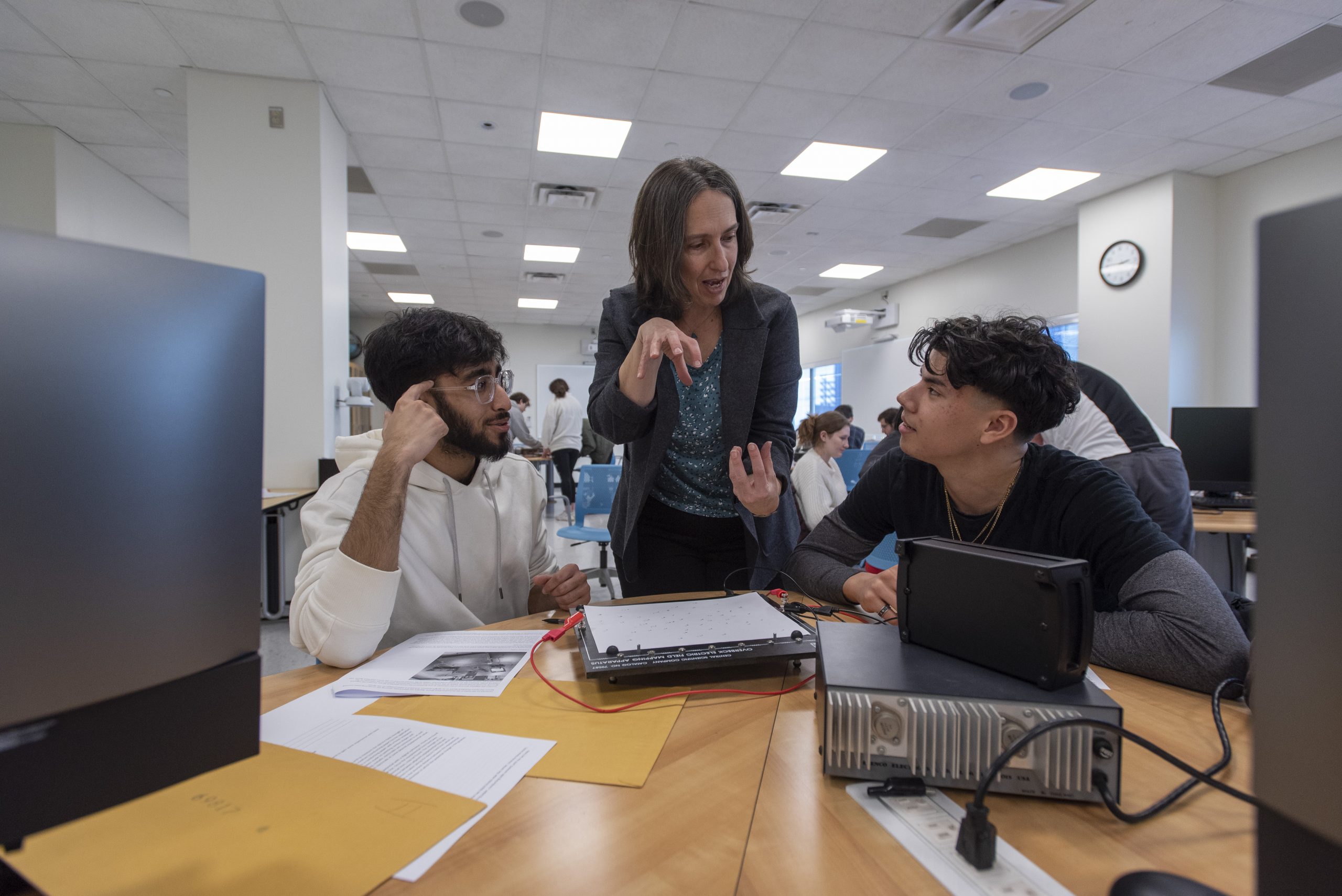 a female professor discussing with two male students a topic