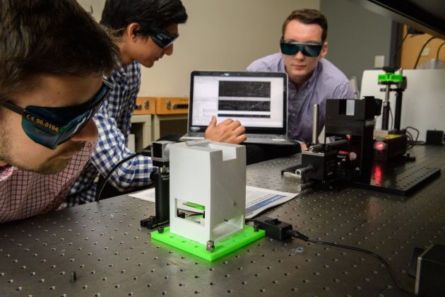 three male students researching laser with lab glasses conducting research