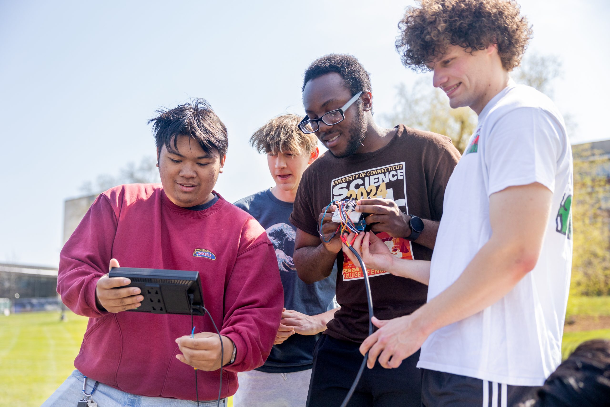 four male students looking at the small screen